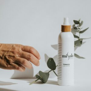 A soothing toner displayed with green leaves on a white surface, showcasing natural beauty.