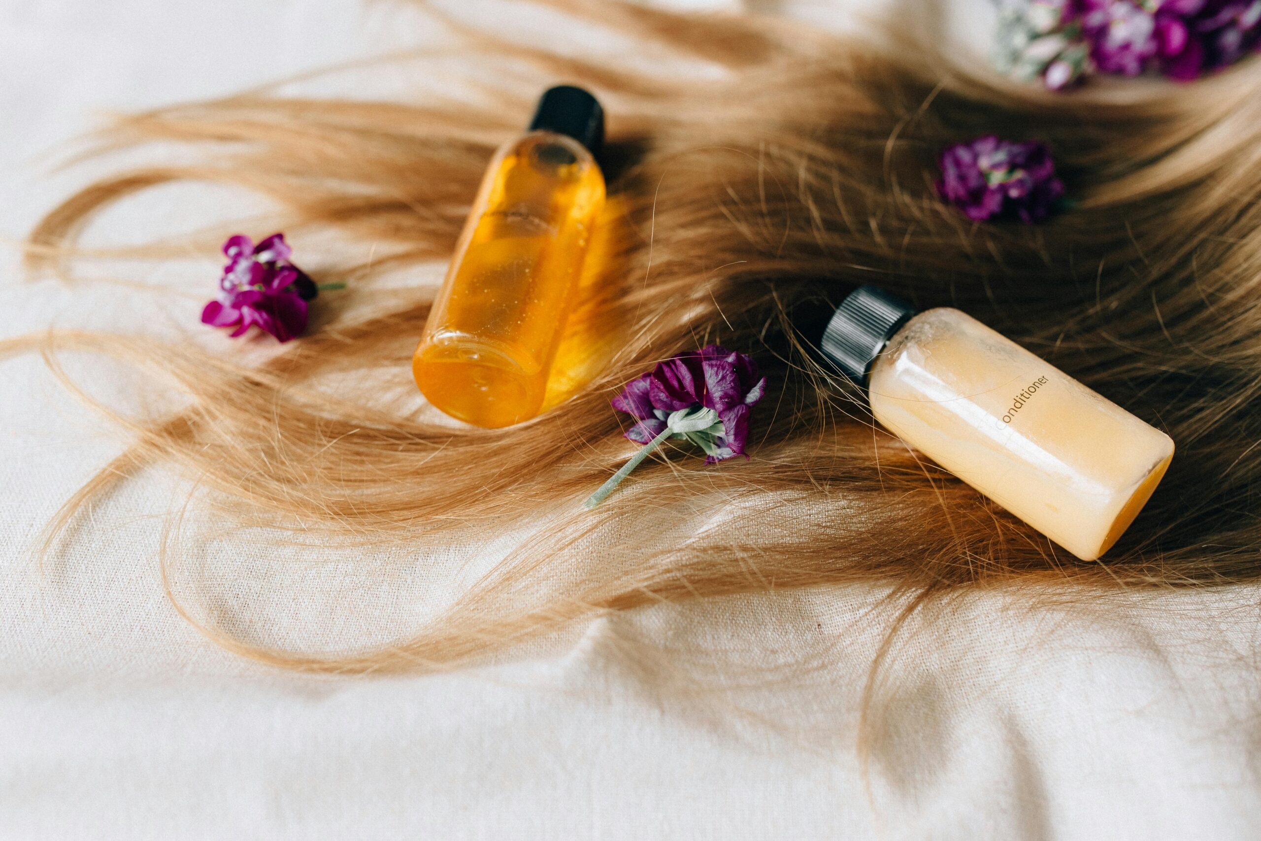 pexels photo 8467963 8467963 Hair care products on a bed of hair and flowers, symbolizing luxury and beauty.