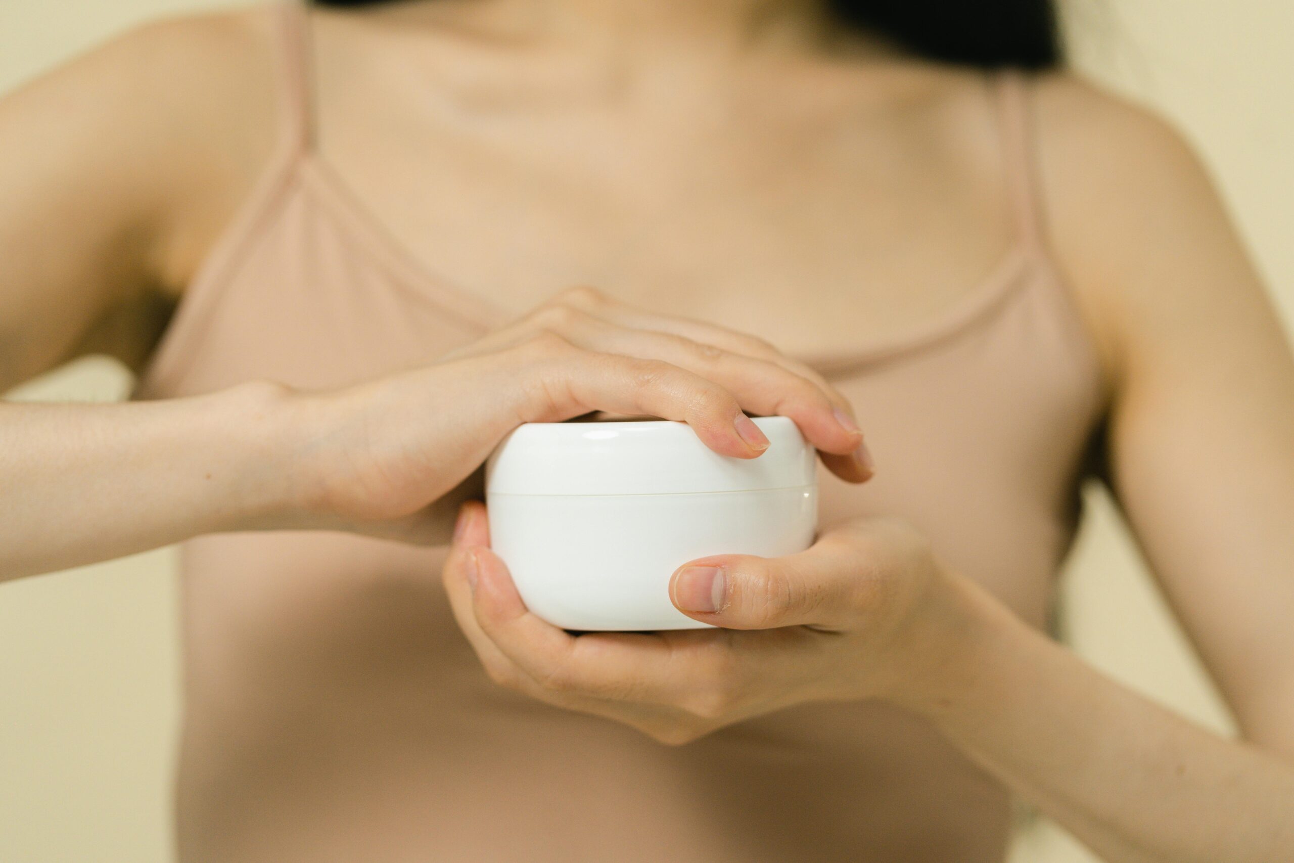 pexels photo 9774608 9774608 Close-up of a woman applying moisturizer with a focus on her hands and the cream container.
